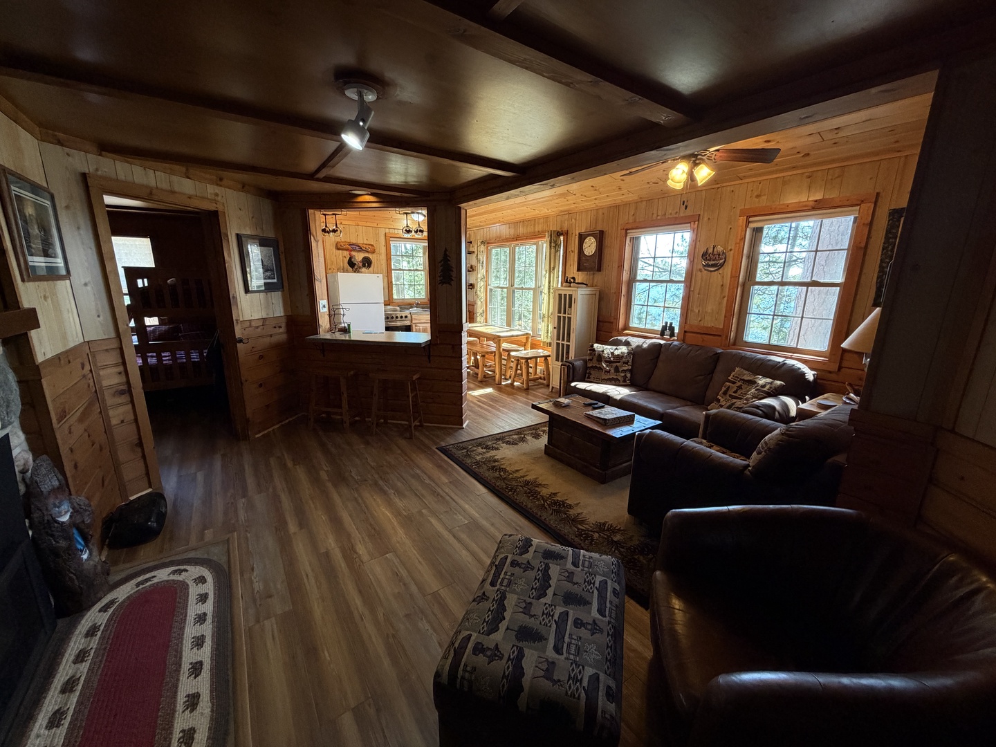 Step into your cozy retreat with warm wood paneling, plush leather seating, and sunlight streaming through large windows. The open layout flows from living space to kitchen and dining, creating a welcoming haven for relaxation.