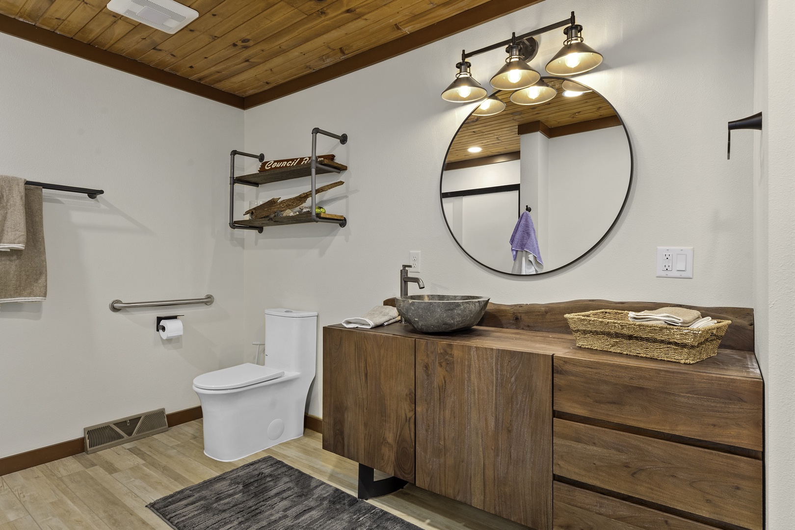 Refresh in your private bathroom with rustic wood tones, a striking stone vessel sink, and industrial-chic lighting that blends modern comfort with warm, natural charm.