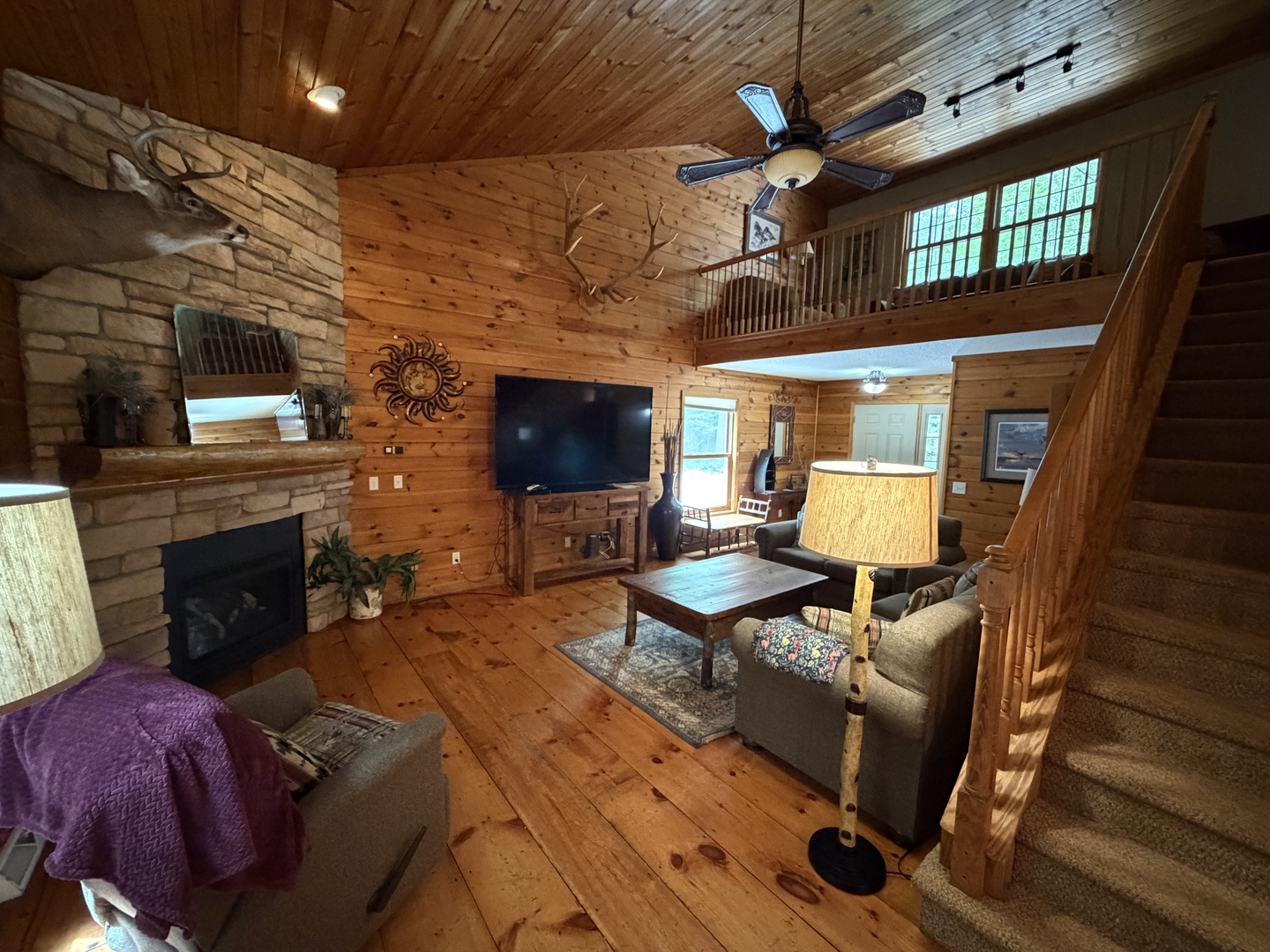 Unwind in this inviting open-concept living room, where rustic wood finishes, a cozy stone fireplace, and comfortable seating create the perfect retreat for your mountain getaway.