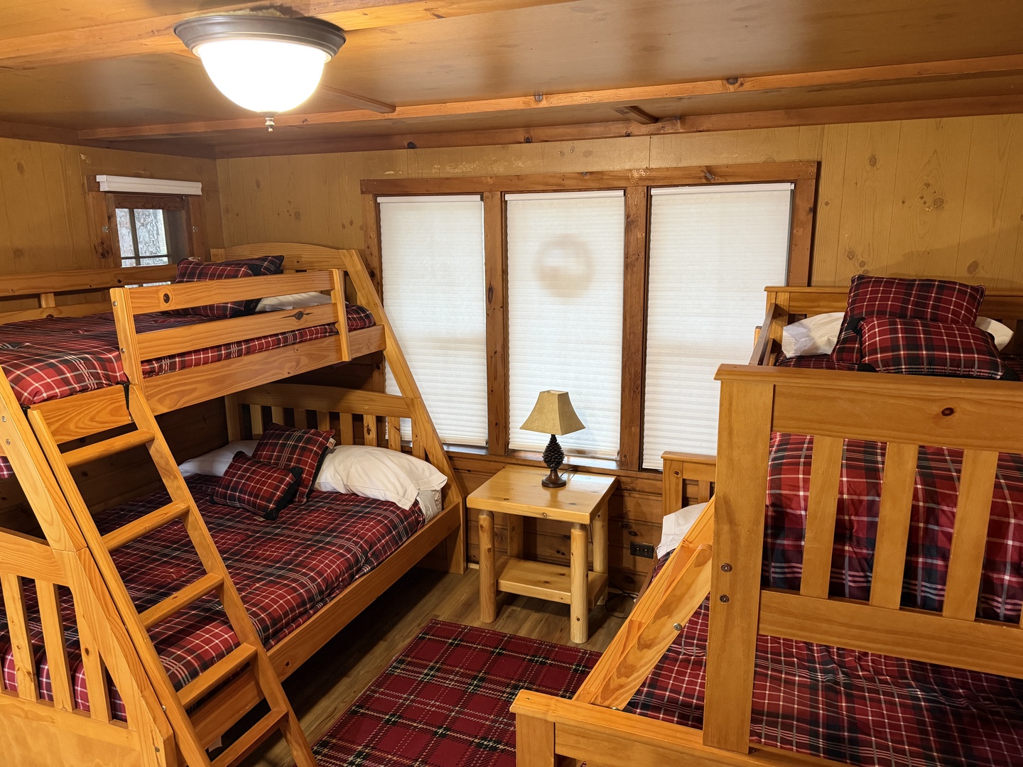 Cozy wooden bunk room with rustic charm and plaid bedding, perfect for families or groups sharing mountain adventures together.