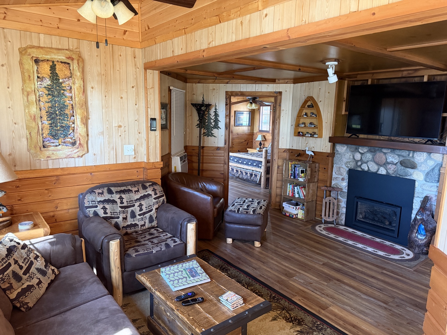 Unwind in your cozy cabin living room with rustic wood walls, plush seating, a crackling stone fireplace, and mountain-inspired décor that invites relaxation after a day of adventure.