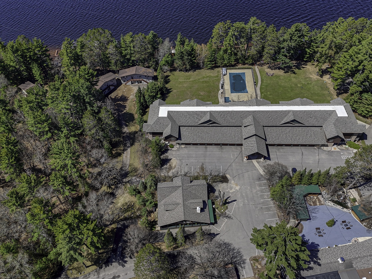 Expansive lakefront property with private pool, ample parking, and direct water access surrounded by mature trees and open lawns.