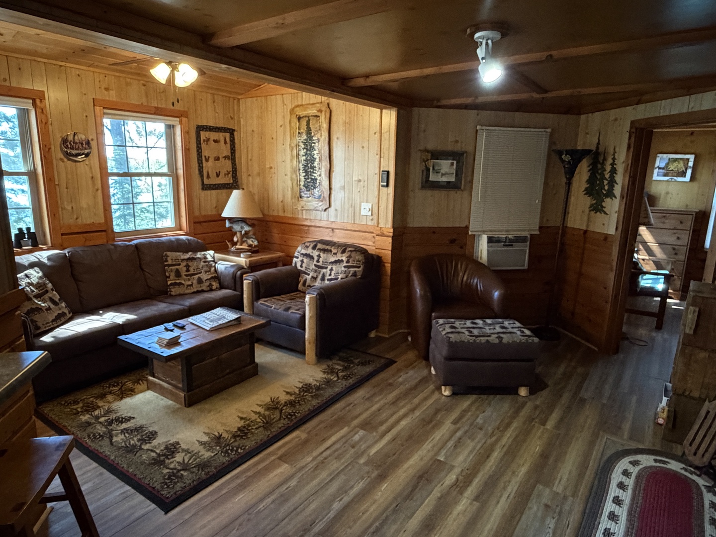 Sink into plush leather sofas surrounded by warm wood paneling. Natural light pours through large windows, illuminating your cozy retreat with rustic charm and inviting comfort.