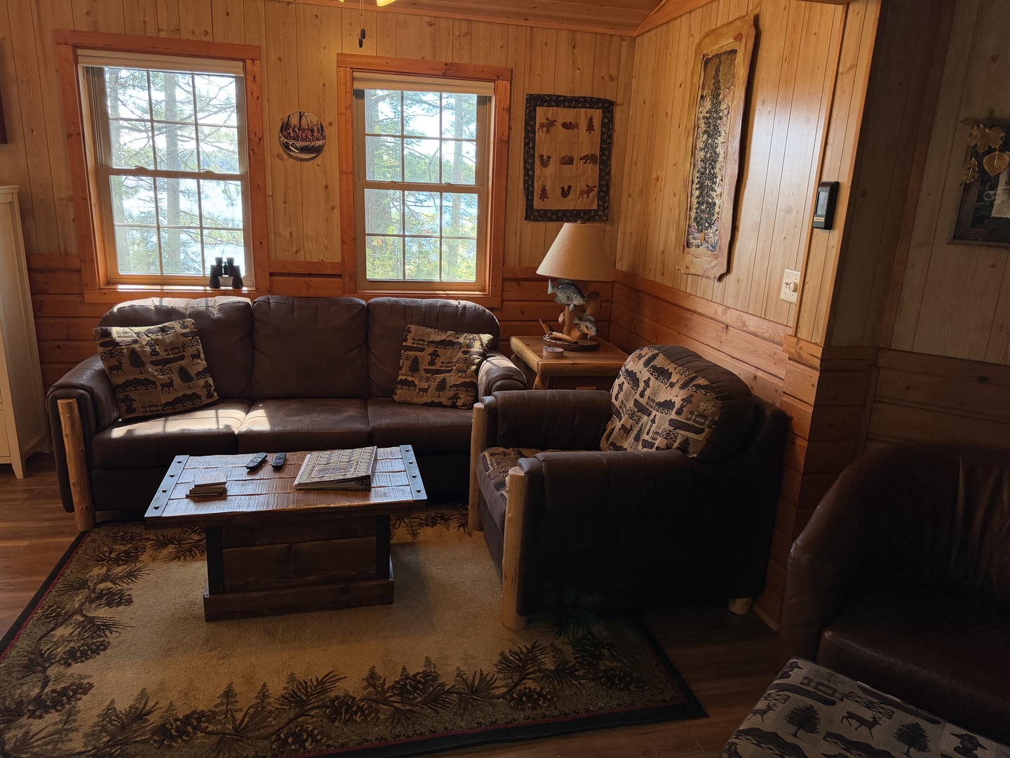 Settle into your cozy living room surrounded by warm knotty pine and natural light. The leather seating and rustic décor invite you to unwind with a book or enjoy treetop views from the windows.