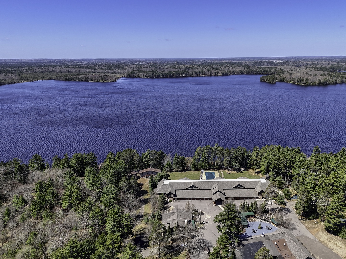 Aerial view reveals a serene lakefront property surrounded by natural forest, offering tranquil waterside access and scenic beauty in a peaceful setting.