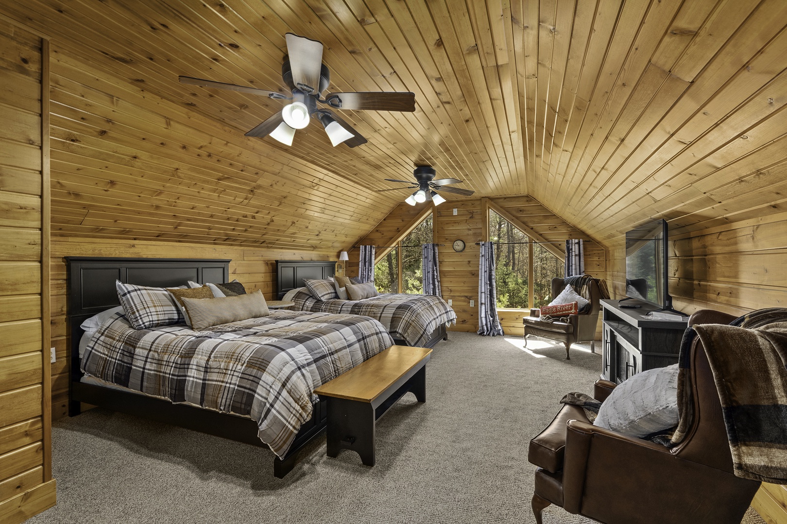 Drift off to sleep in this spacious bedroom where rustic wood beams meet cozy plaid bedding, and natural light filters through tall windows
