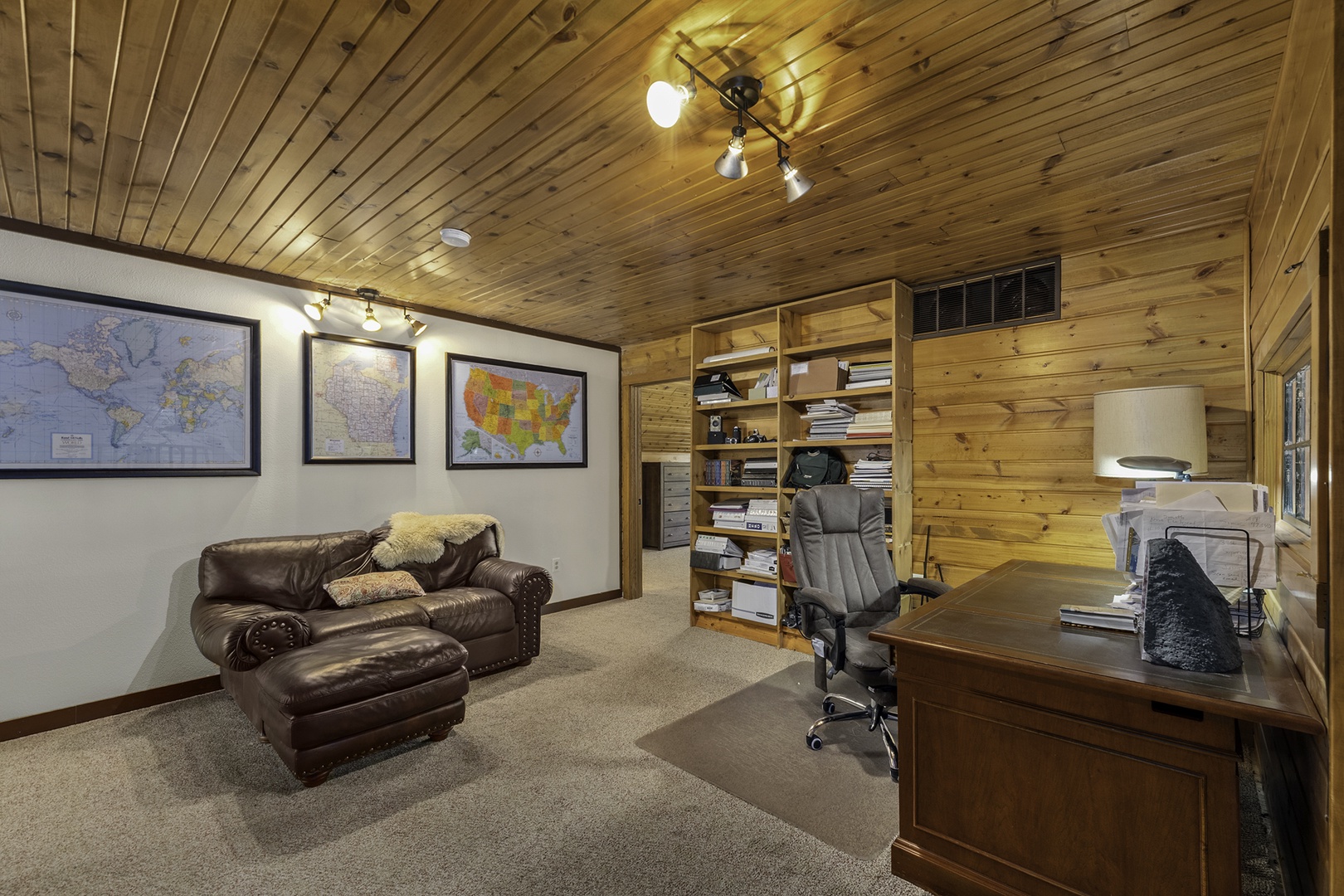 Your private workspace blends rustic charm with modern comfort—leather seating invites relaxation, while a full desk setup keeps you productive beneath warm wood-paneled ceilings.