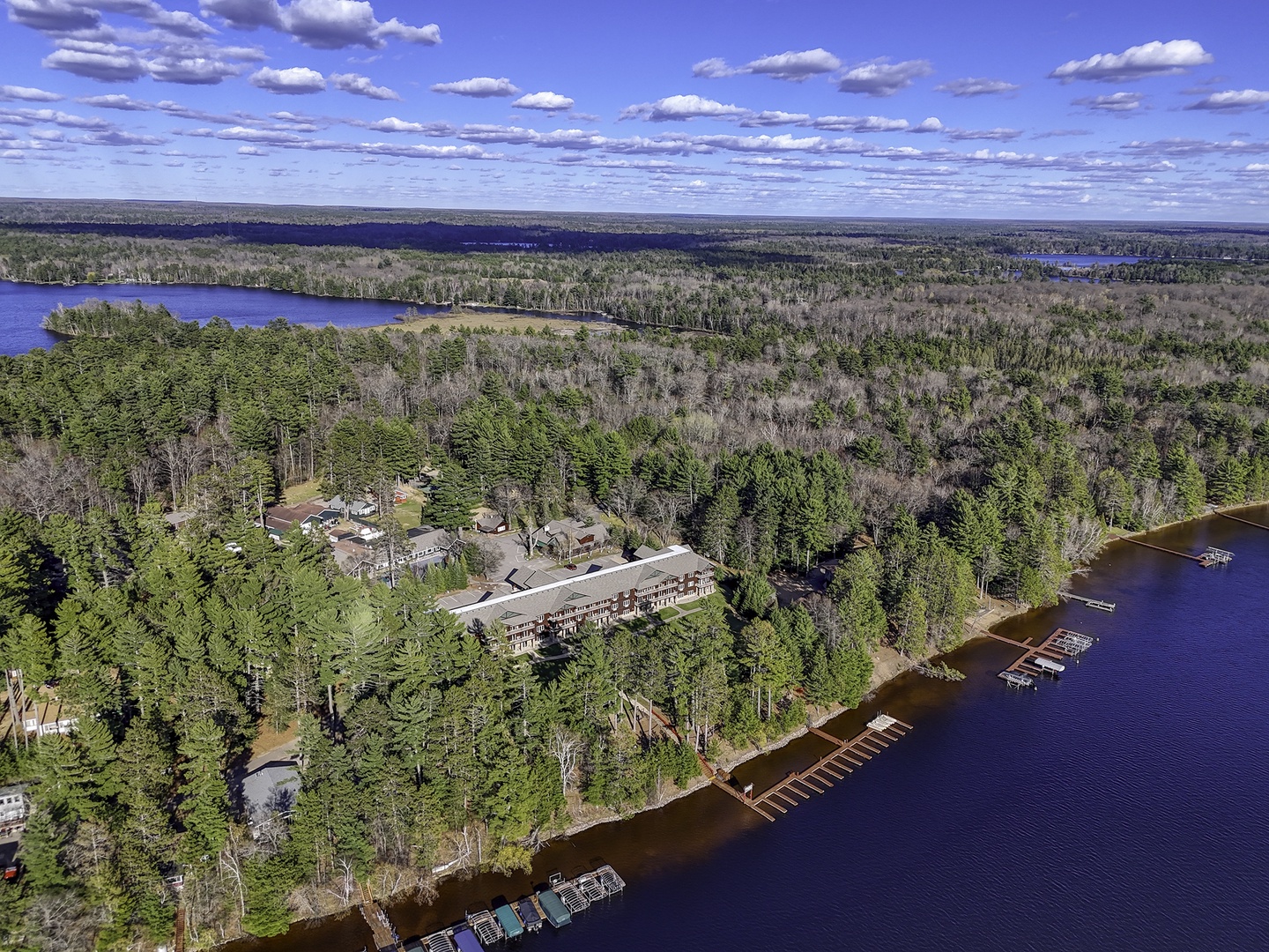 Aerial view of the lakefront property nestled among towering pines, with private docks and boat slips lining the pristine waterfront.