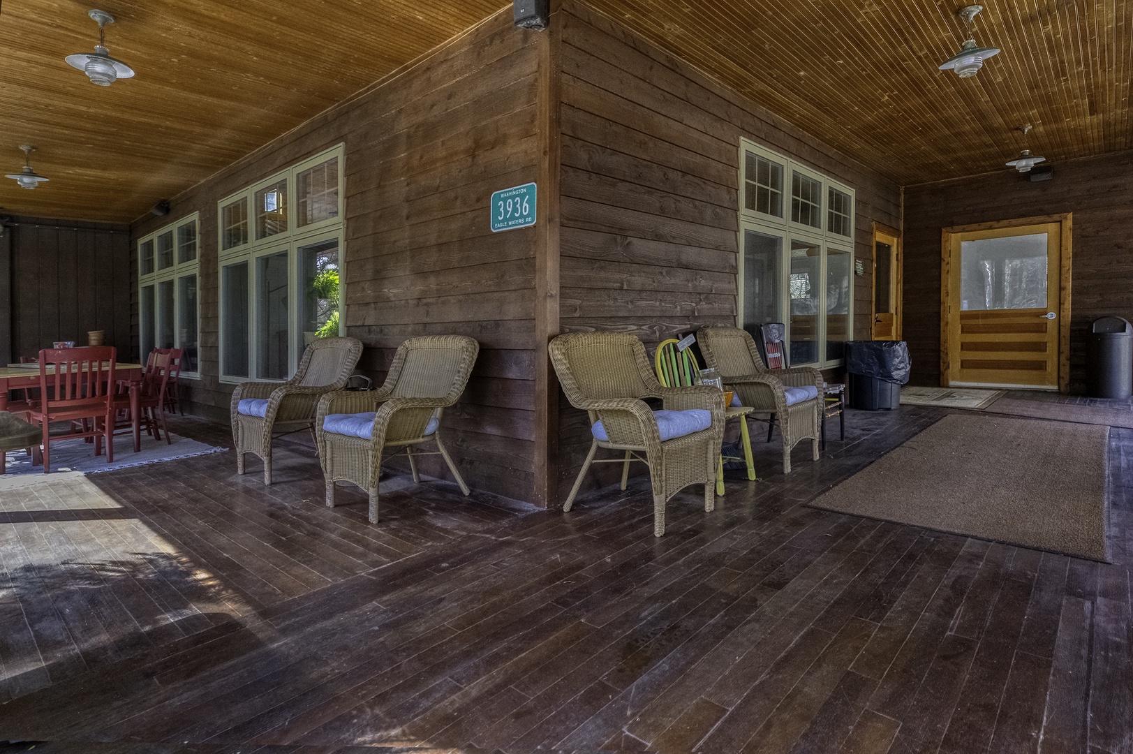 Covered front porch with wicker seating and rustic wood plank walls creates a welcoming retreat where you can relax and enjoy peaceful moments before exploring the area.