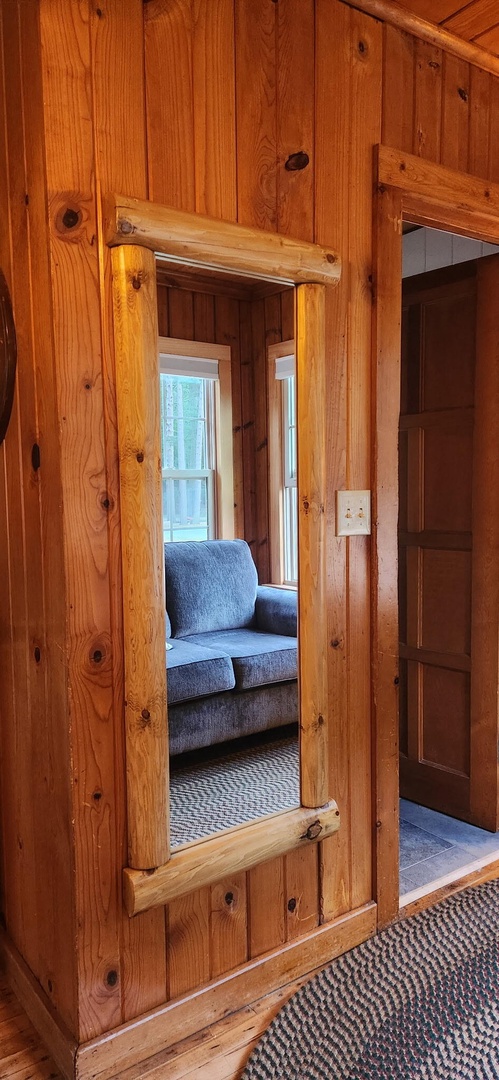 Step inside your cozy log cabin retreat, where warm wood walls and comfortable furnishings create the perfect escape. Sunlight filters through the windows, inviting you to settle in and unwind.