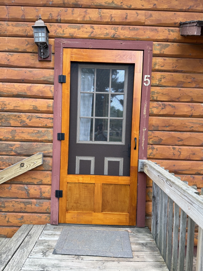 The entrance to your unit, marked with clear identification. The warm wooden details and covered porch create a welcoming arrival point.