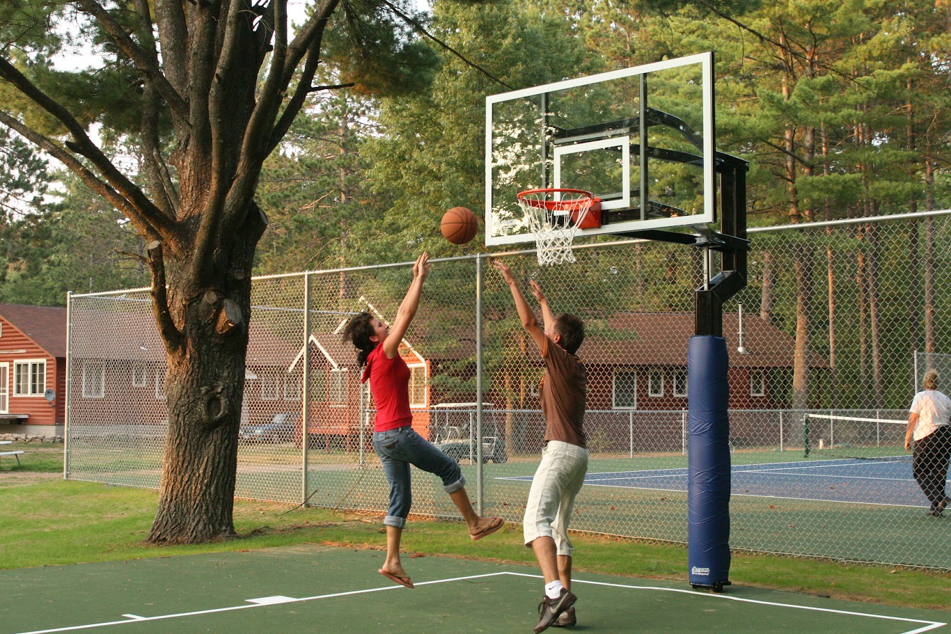 Challenge friends to an energetic basketball game on the outdoor court, surrounded by peaceful trees and open space.