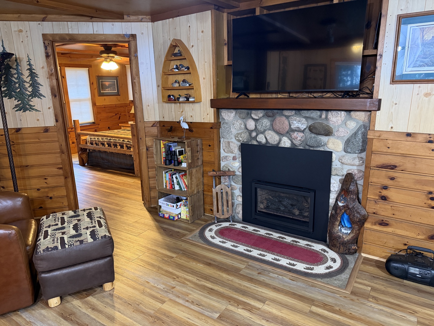 Cozy up by your stone fireplace in this charming cabin living room with warm wood accents, a flat-screen TV, and rustic touches that make you feel right at home.