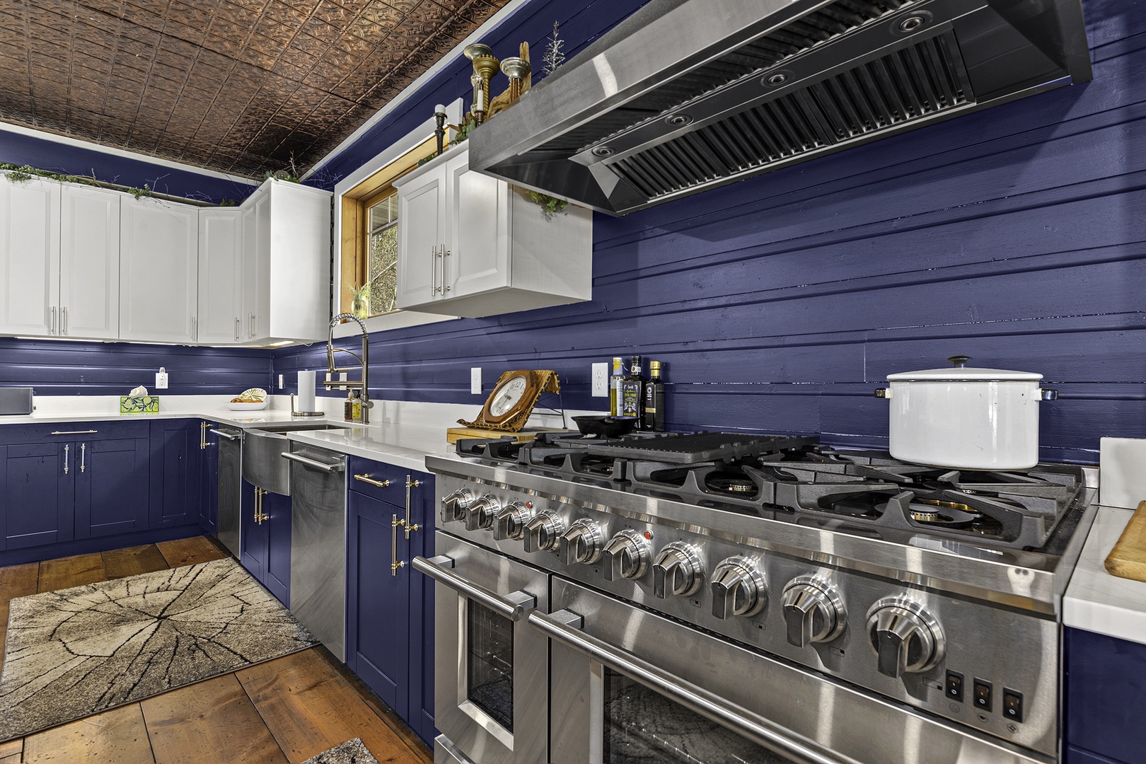 Your gourmet kitchen features a professional-grade stove, sleek white counters, and rich navy cabinetry, perfect for crafting memorable meals during your stay.