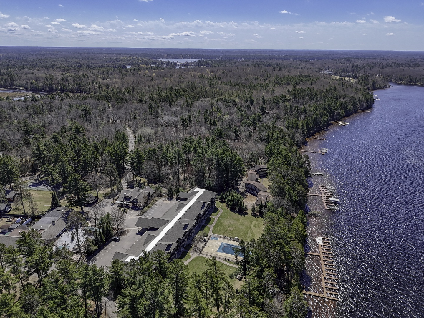 A lakefront property nestled among towering pines, offering  docks and serene views of pristine waters surrounded by dense forest and natural wilderness.