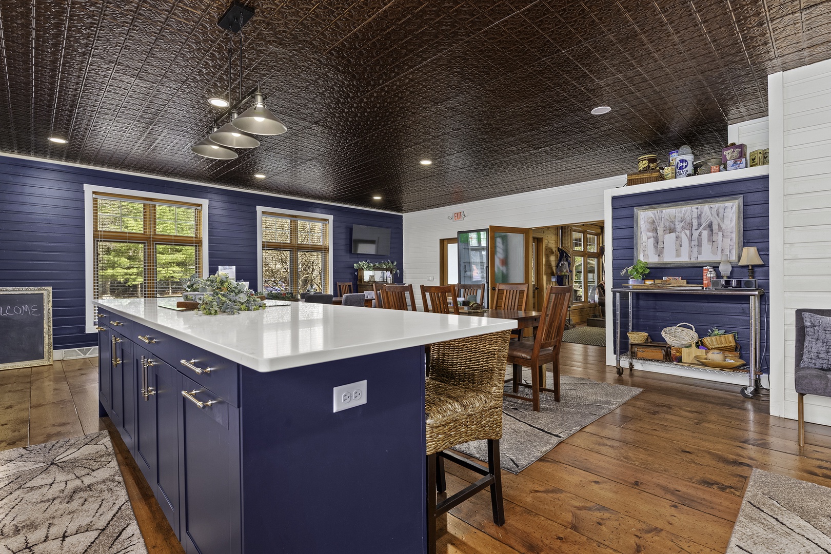 Gather around this stunning kitchen island with its gleaming white countertop, perfect for prepping meals or sharing stories. The rich navy blue cabinetry and warm wood floors create an inviting space where your group can cook and connect together.