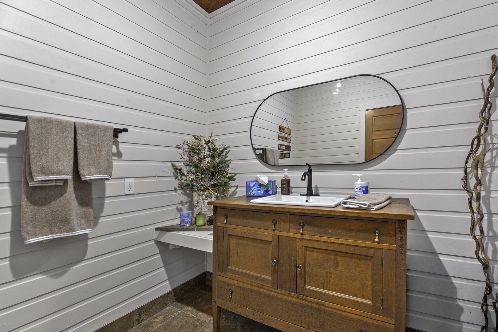 Step into your farmhouse-style bathroom where rustic wood vanity meets modern charm. Fresh linens await on the towel rack, and a skylight above bathes the space in natural light.