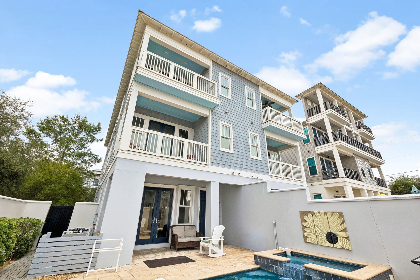 This coastal-style property features multiple balconies and a private pool area with decorative wall art, offering a blend of modern comfort and beachside charm in a peaceful setting.