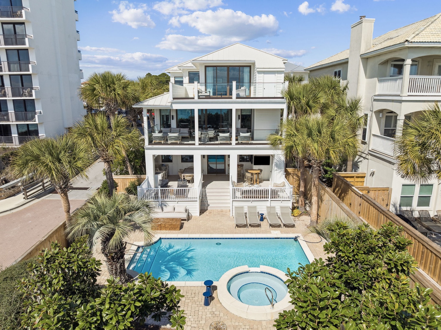 Stunning beachside estate features a sparkling private pool and spa surrounded by tropical palms and multiple outdoor living spaces.