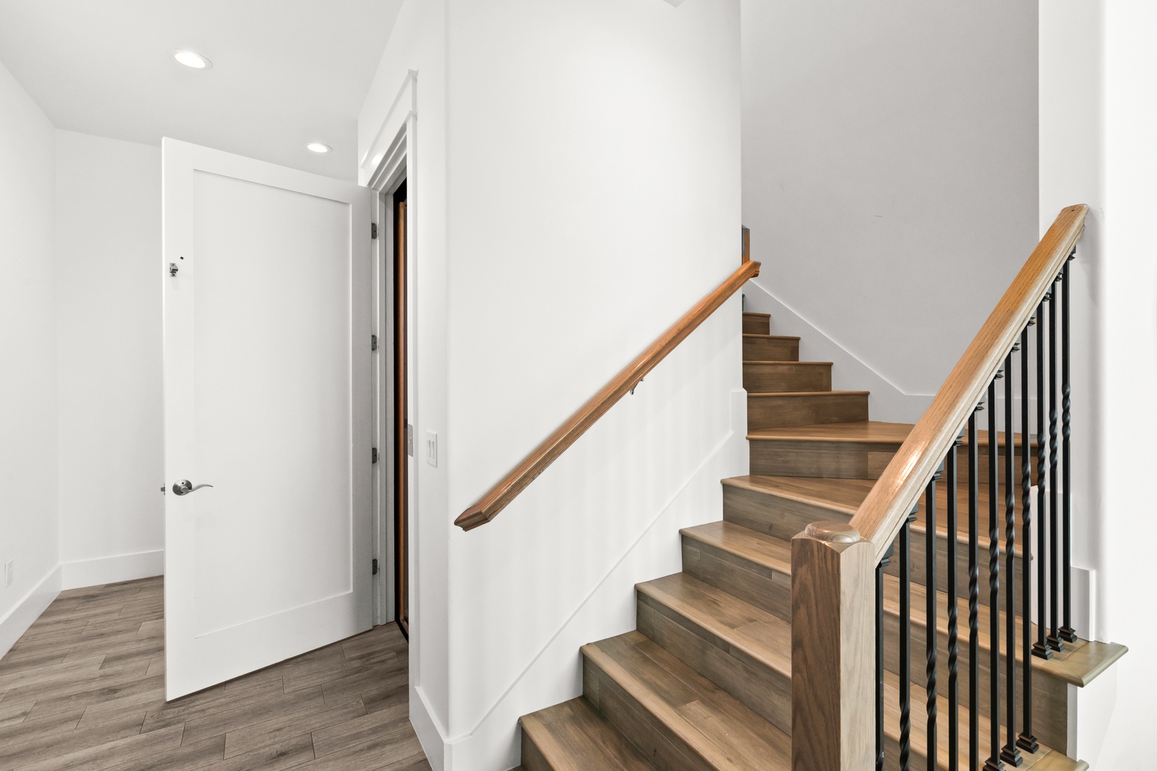 Bright, modern entryway and staircase with warm wood tones and clean lines inviting you upstairs.
