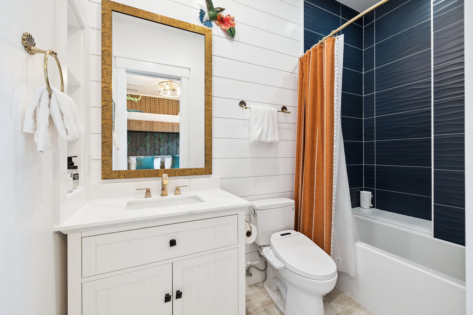 Step into your beautifully designed bathroom featuring coastal charm with white shiplap walls, elegant gold-framed mirror, and luxurious tub.