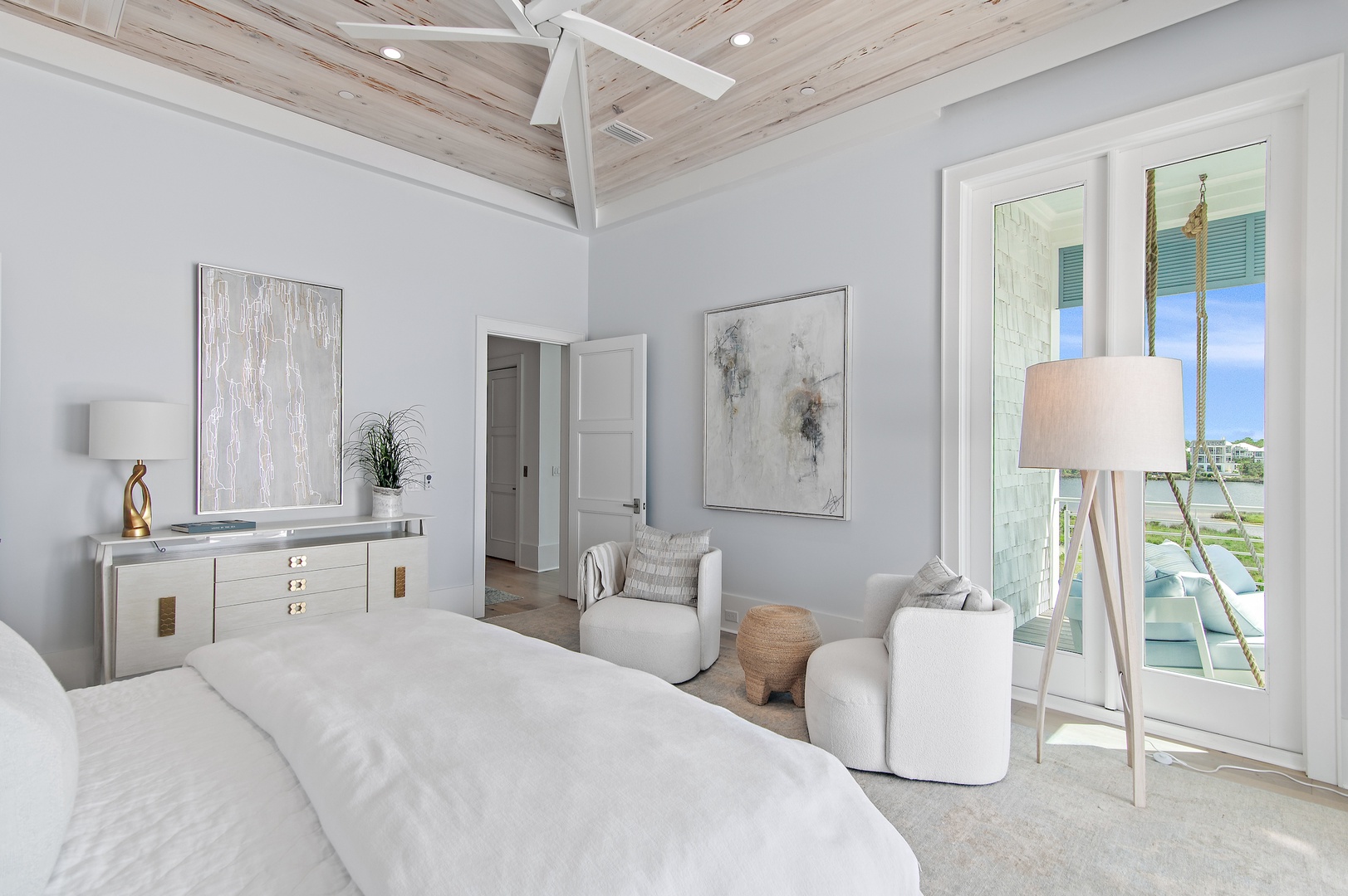 Your serene coastal bedroom invites you to unwind beneath a soaring whitewashed wood ceiling. Step through French doors to your private balcony and soak in breathtaking water views.