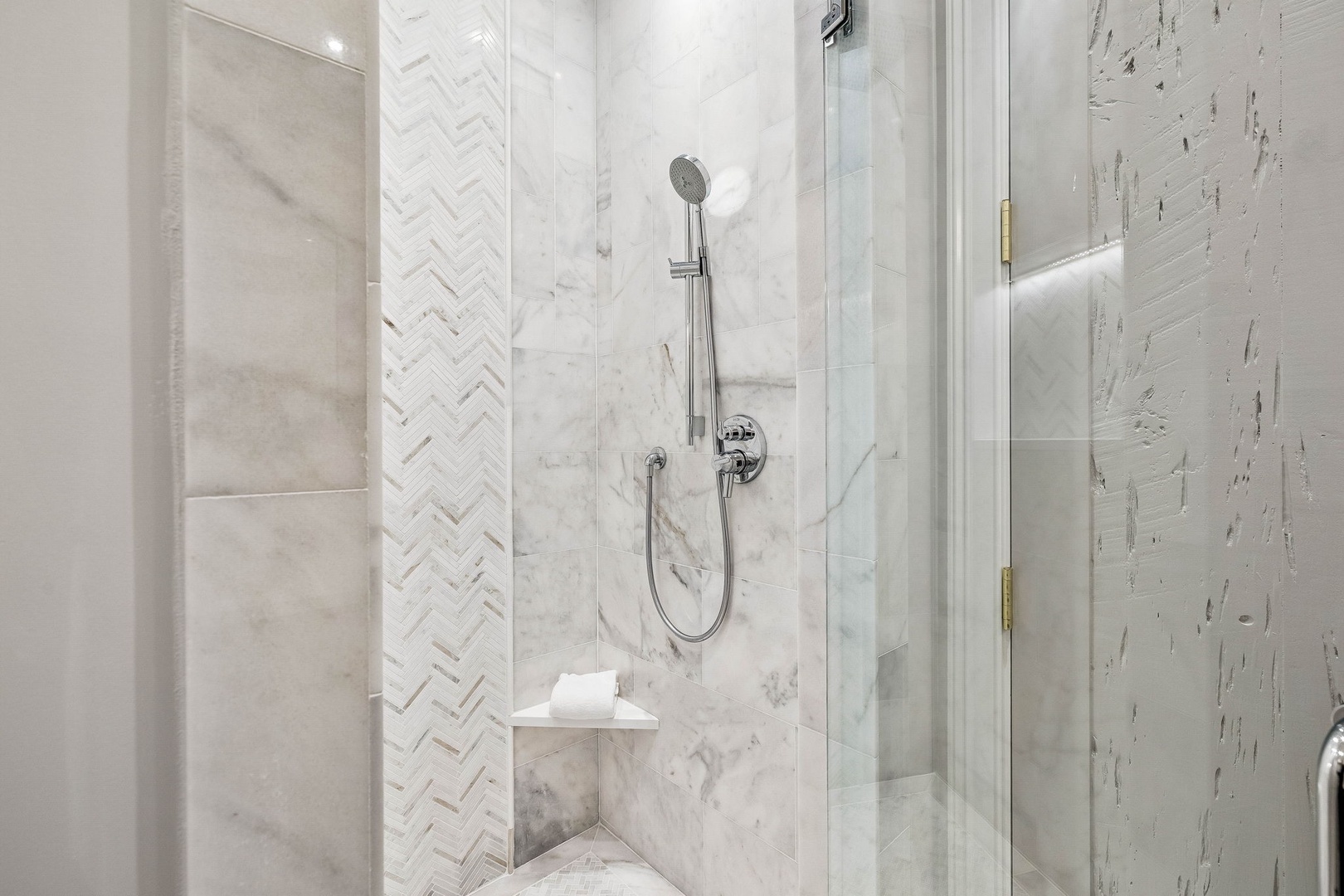Sleek marble shower with herringbone accent tile and modern fixtures—your personal spa awaits after a day exploring.