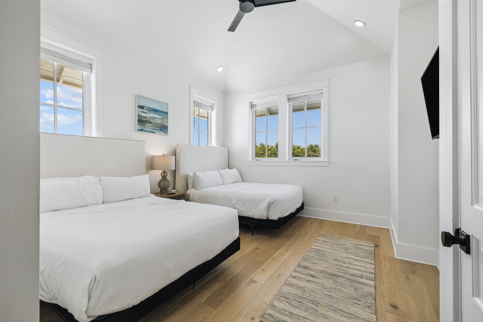 Rest easy in this bright, airy bedroom with two comfortable beds, a gentle ceiling fan, and natural light streaming through the windows. Perfect for your peaceful getaway.