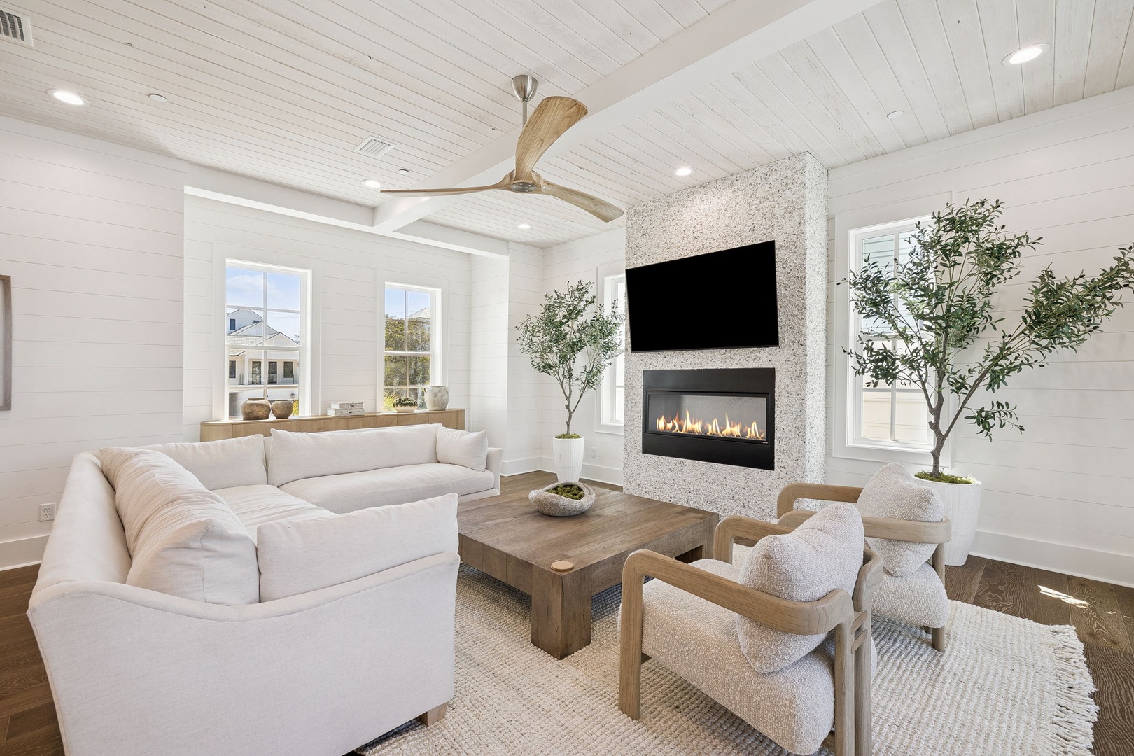 Sink into plush seating by your modern fireplace while warm flames dance beneath the wall-mounted TV in this elegant retreat.