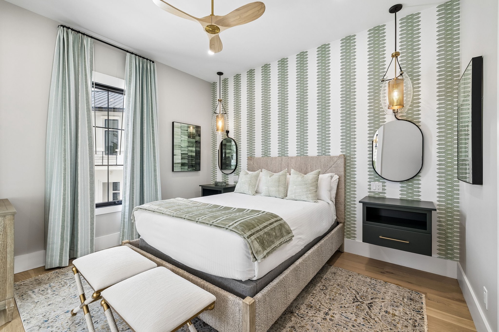 Sink into crisp linens and layered textures as natural light pours through sheer curtains, inviting you to unwind beneath the glow of elegant pendant lighting.