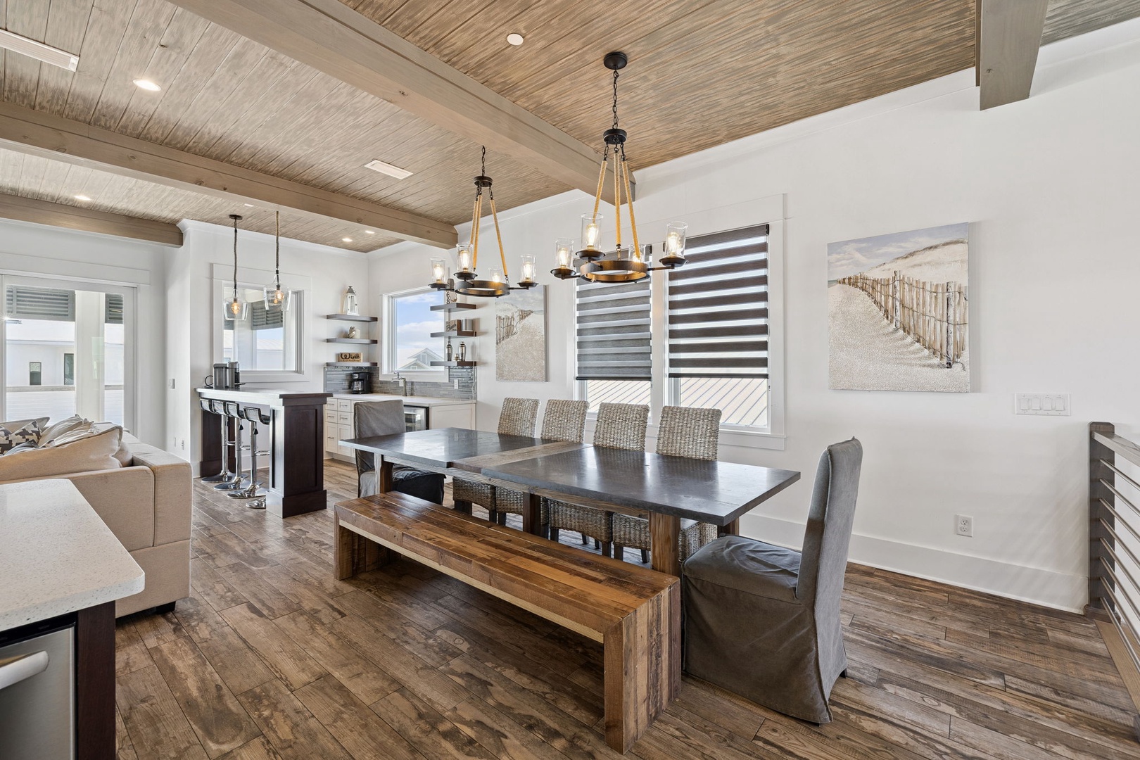 Gather around the sleek dining table under rustic wood-beam ceilings, where warm pendant lights create perfect ambiance for your memorable meals together.