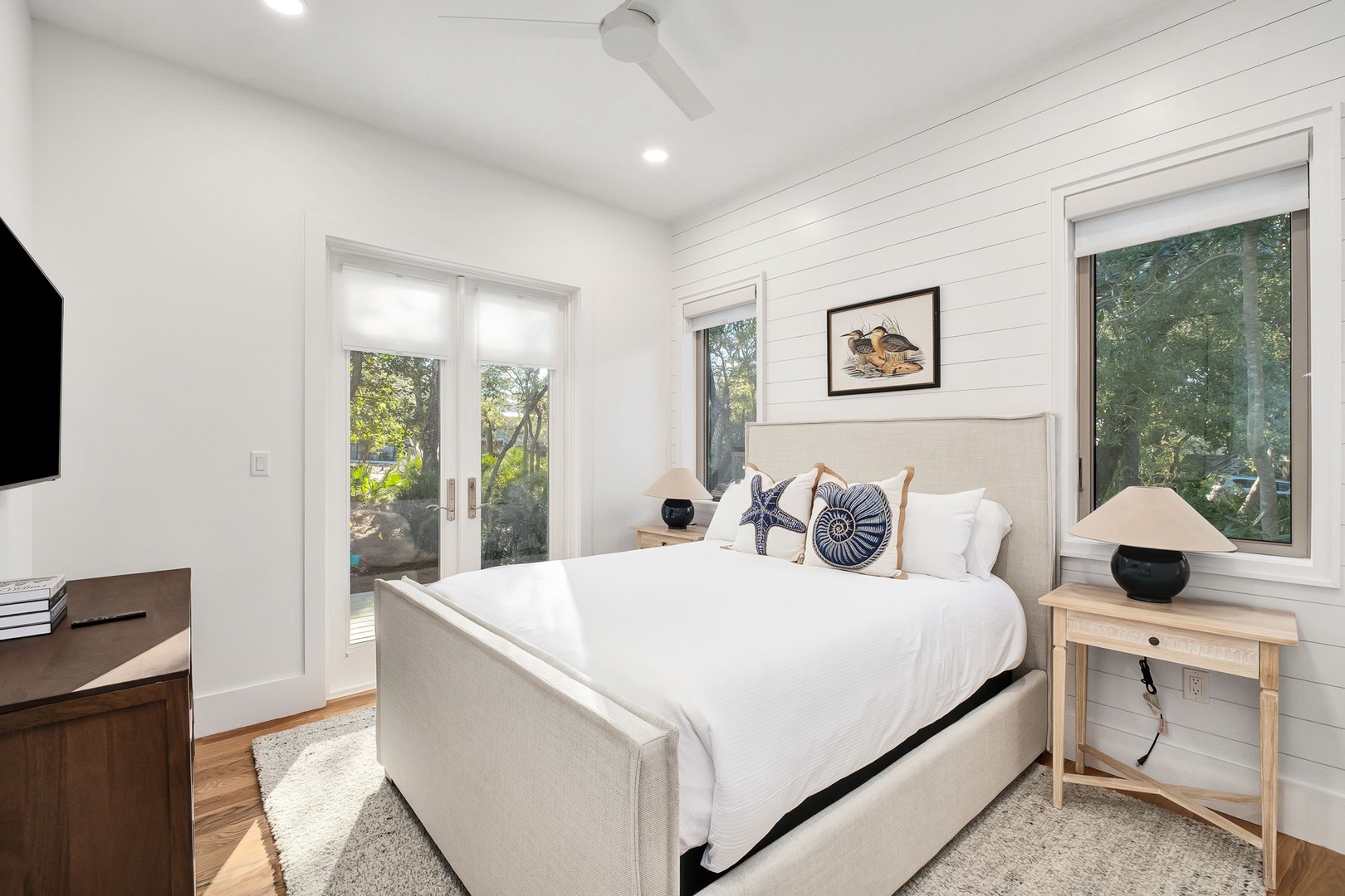 Relax in your bright bedroom with crisp linens, nautical touches, and garden views through French doors.