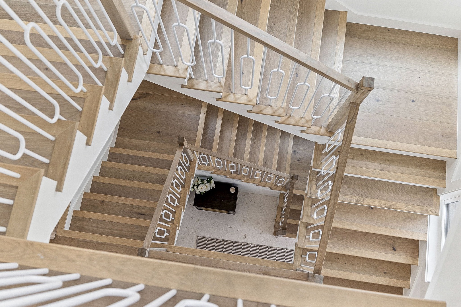 Elegant wooden staircase with white railings creates a stunning architectural centerpiece in your vacation home.