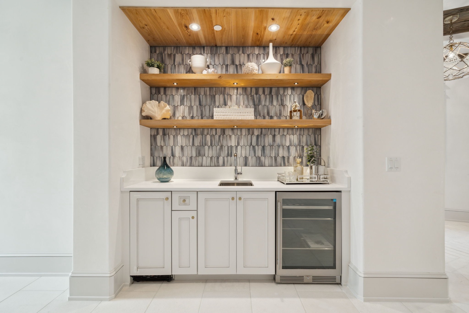 Your private wet bar features a stunning wood-beamed ceiling, chic geometric tile backsplash, and open shelving for your favorite refreshments—ideal for unwinding after exploring all day.