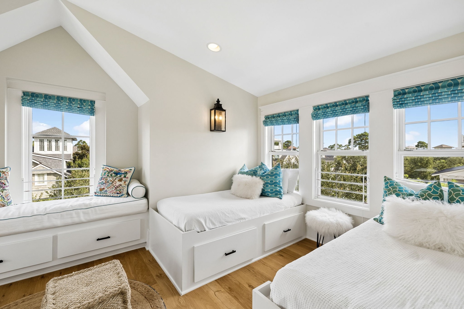 Settle into your bright coastal retreat with plush window seat beds that frame serene neighborhood views. Crisp white linens and pops of turquoise invite you to unwind in comfort.