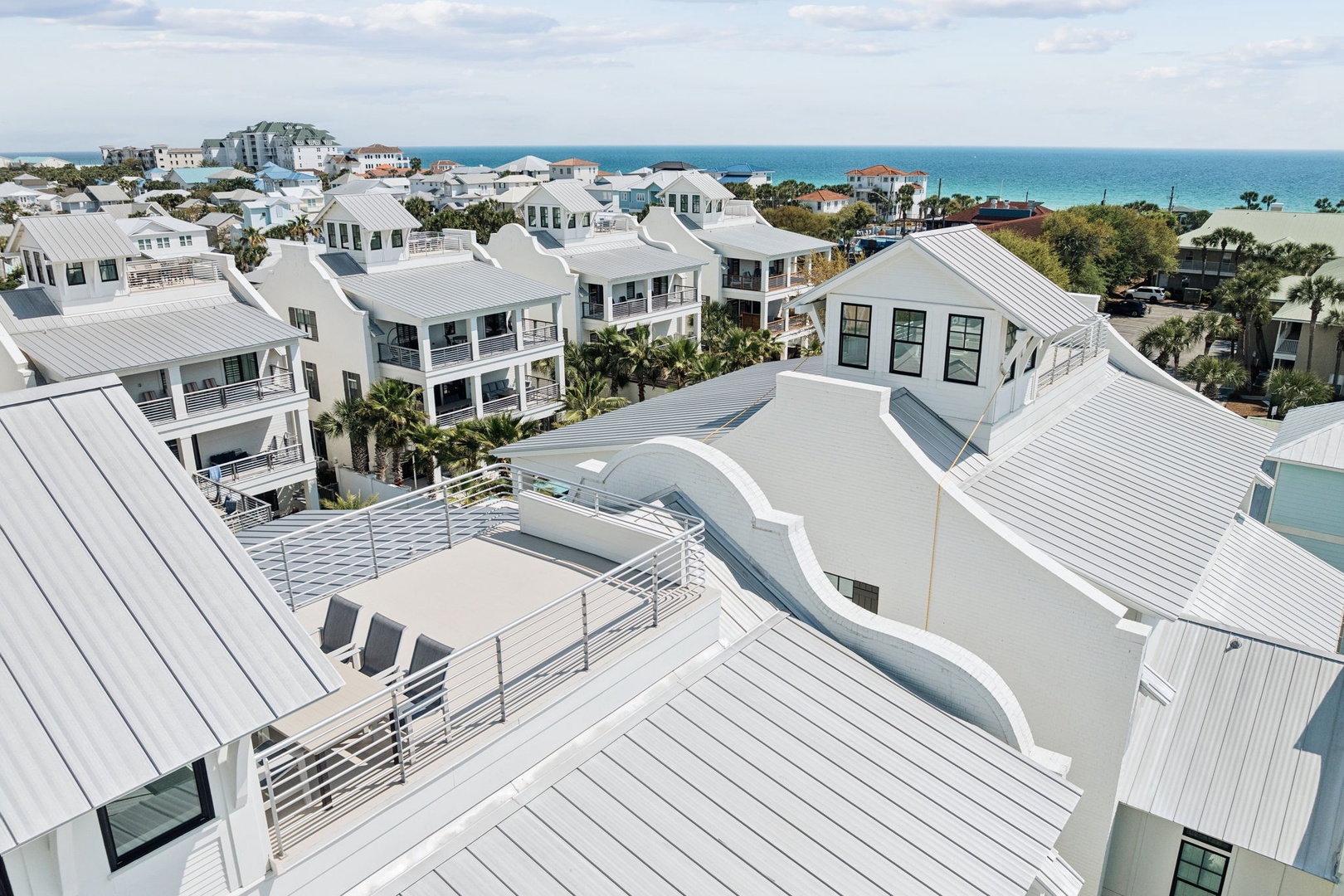 Stunning coastal development with modern white buildings featuring metal roofing and elegant architecture, located steps from pristine turquoise waters.