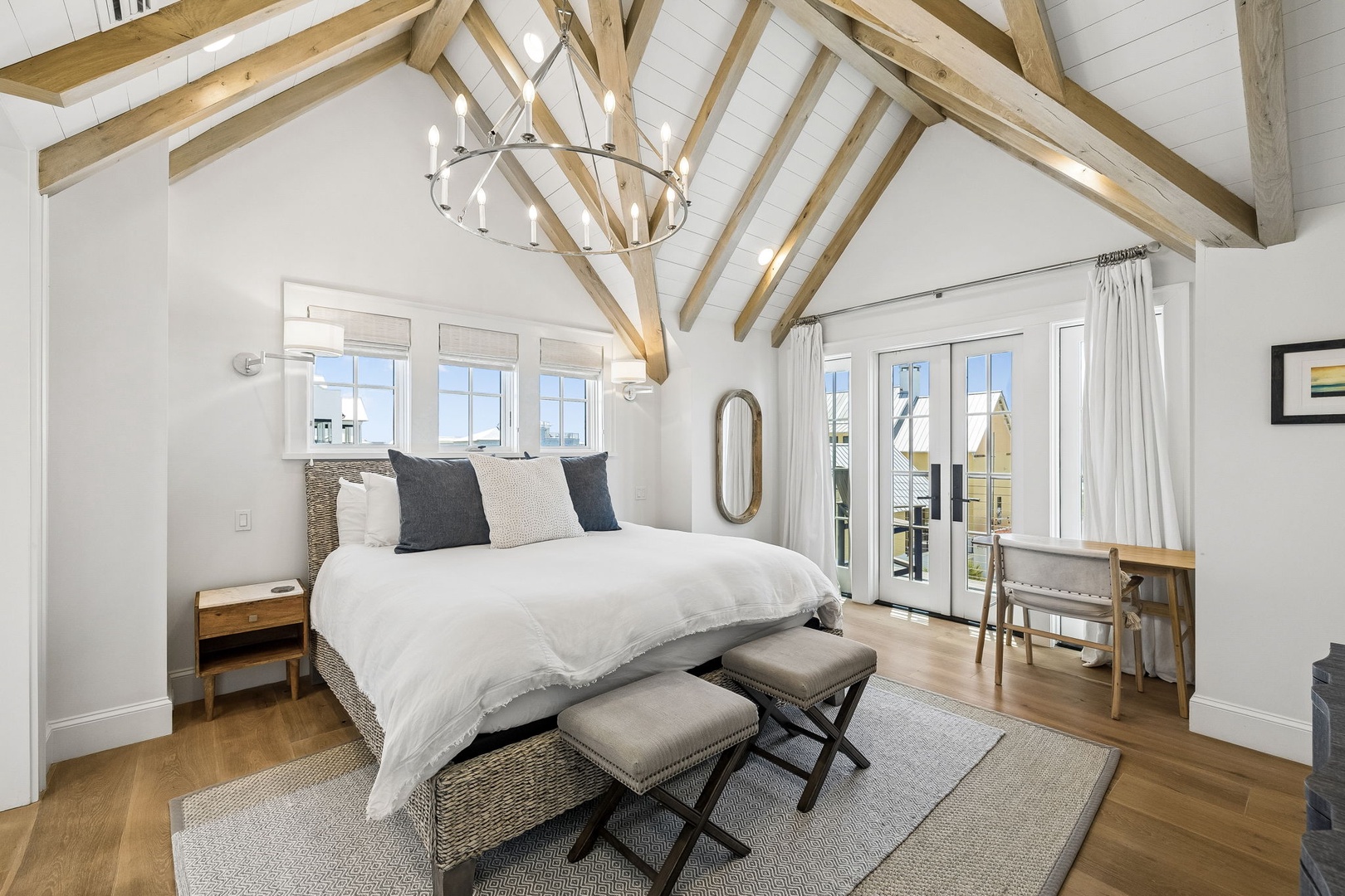 Drift off under striking vaulted beams in this sun-drenched bedroom with plush bedding, stylish seating, and your own balcony doors opening to fresh air and peaceful views.