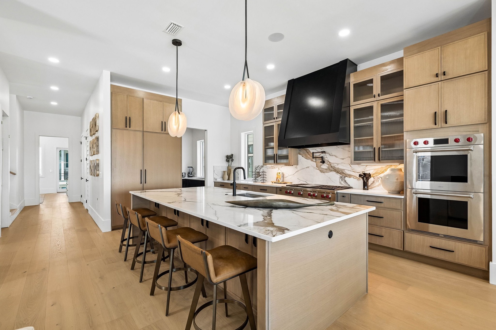 Gather around this stunning gourmet kitchen where light wood cabinetry meets luxurious marble countertops. Your culinary dreams come alive with professional-grade appliances and plenty of space for creating and entertaining together.