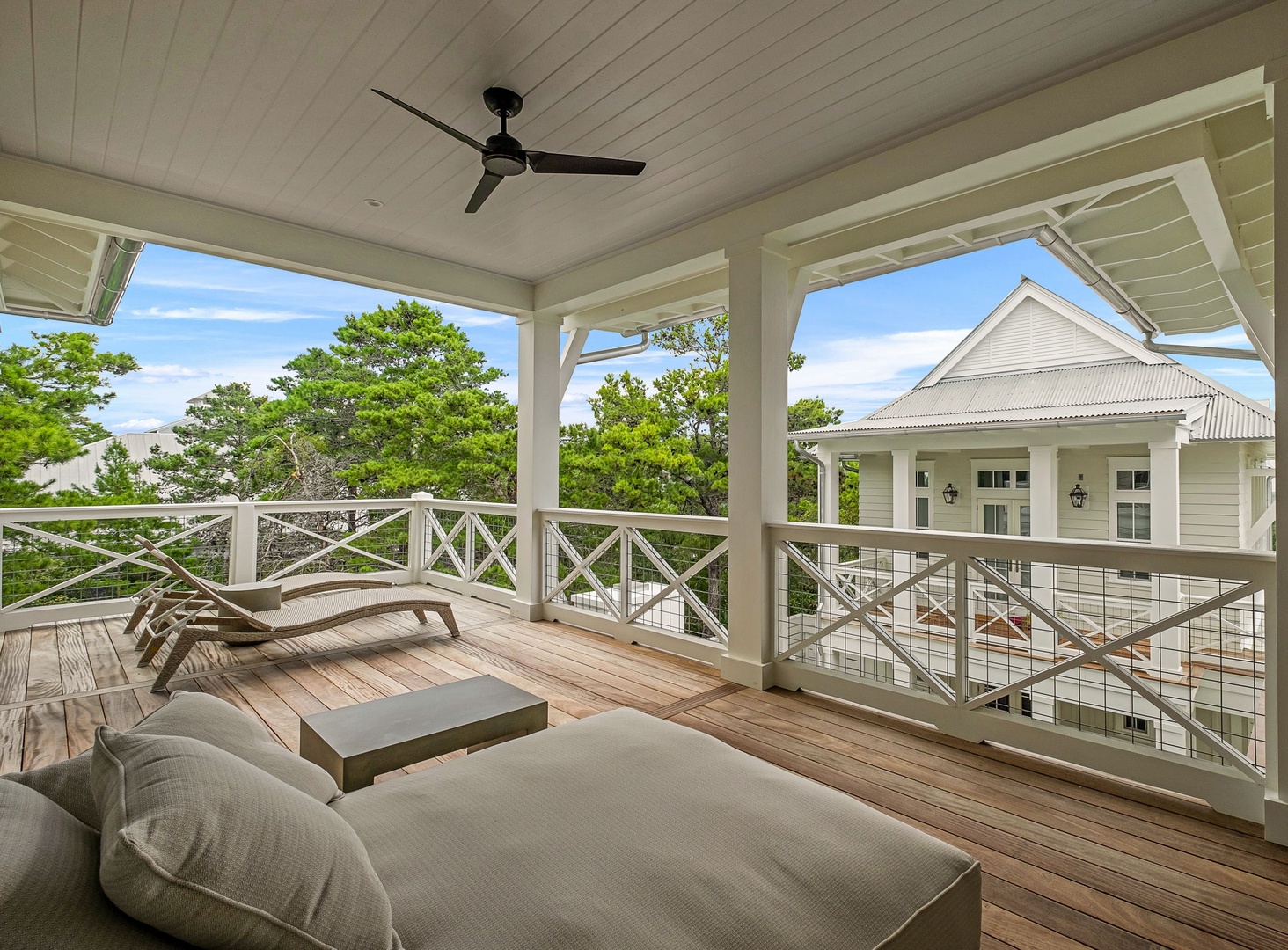 Unwind on your private covered balcony with open views of lush greenery and neighboring architecture. A ceiling fan keeps things comfortable as you relax on cushioned loungers and take in the peaceful surroundings.