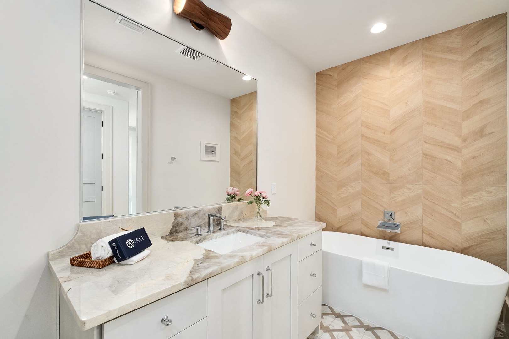 Soak in your elegant marble bathroom featuring a luxurious soaking tub and beautiful herringbone wood accent wall.