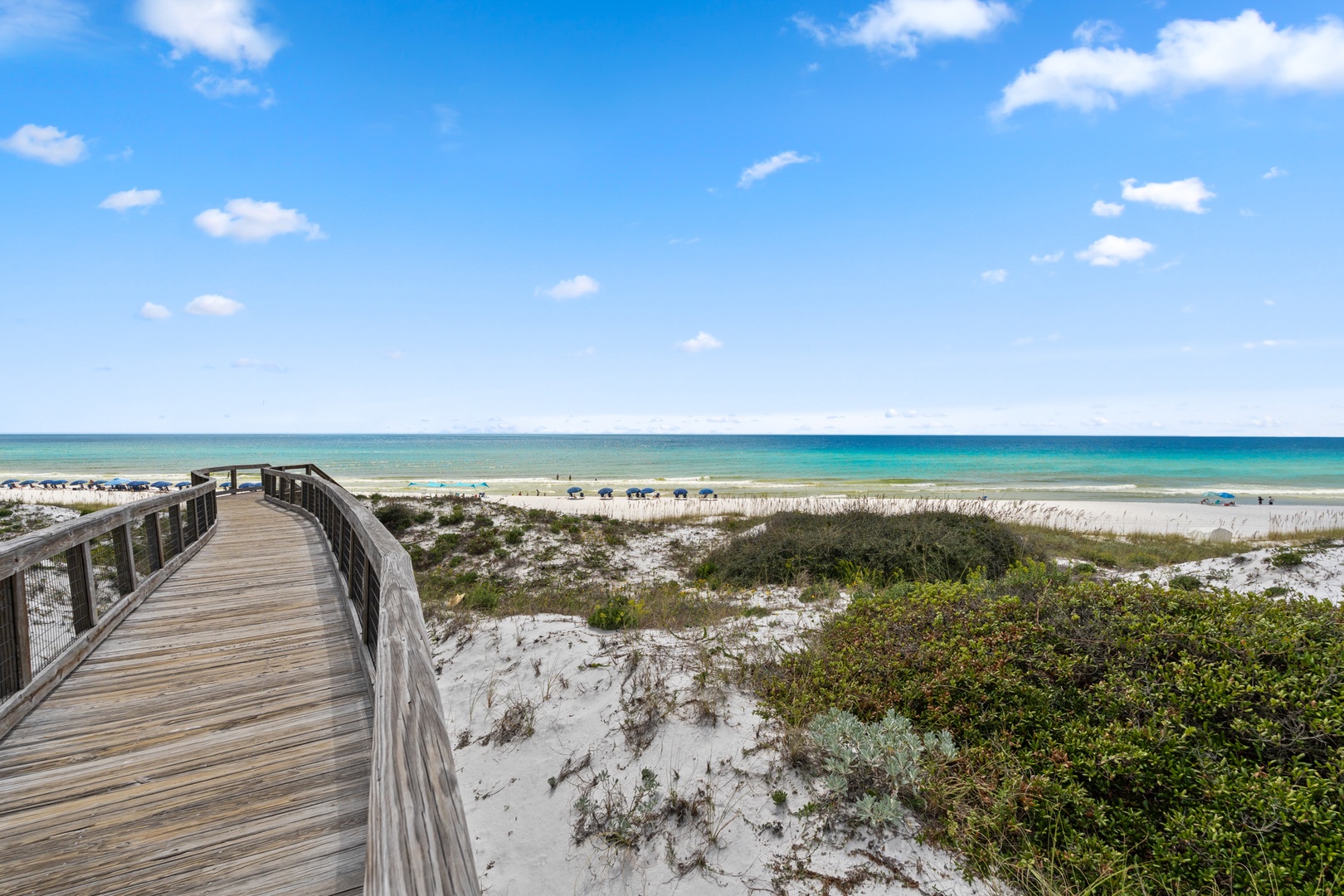 The property is located near a pristine beach with white sand dunes, coastal vegetation, and a scenic boardwalk providing access to turquoise waters and expansive shoreline.