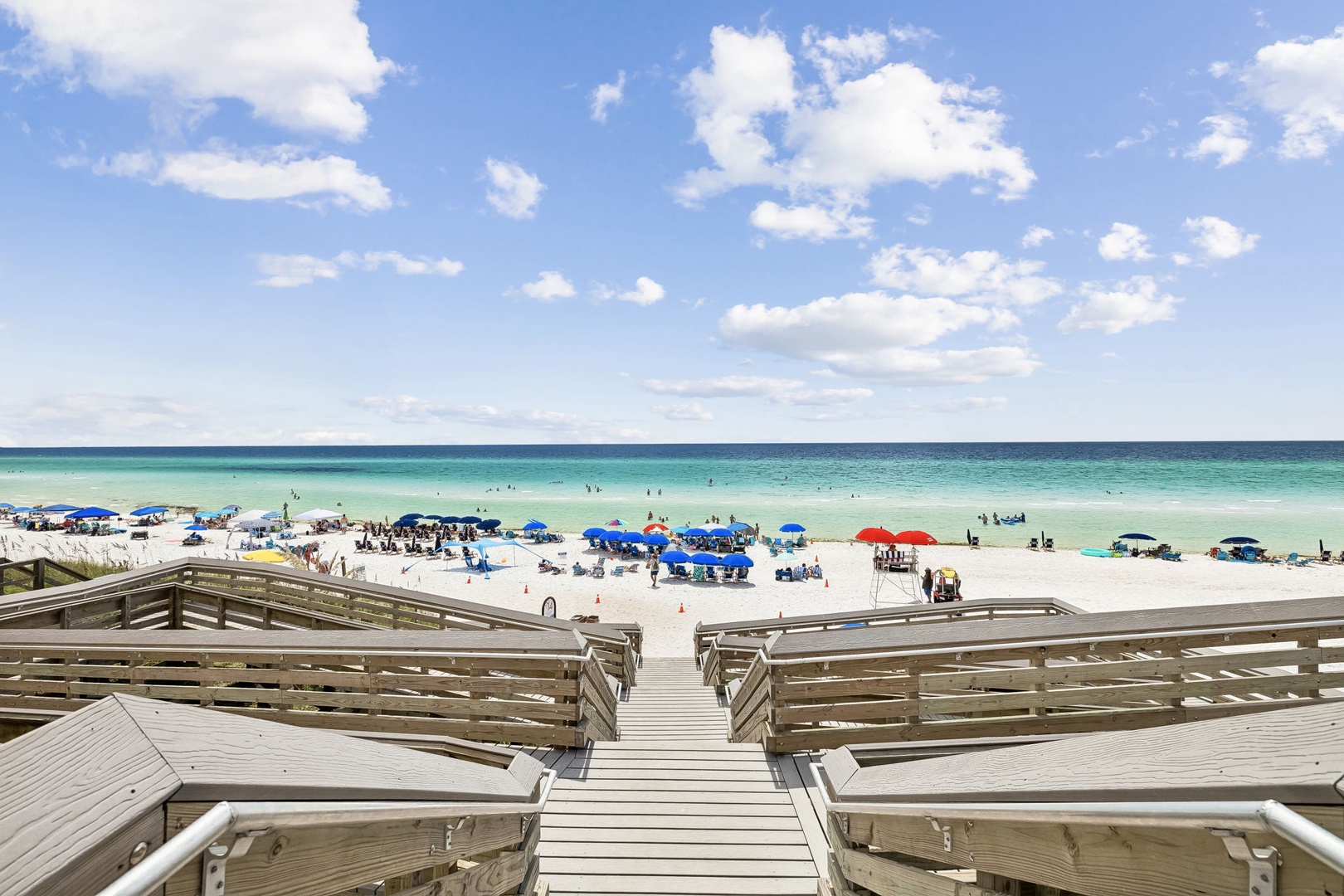 A pristine stretch of white sand meets turquoise waters, with beach access just steps away from the property. The surrounding area features a lively beach atmosphere with umbrellas and sunbeds, perfect for soaking up the Florida sunshine.