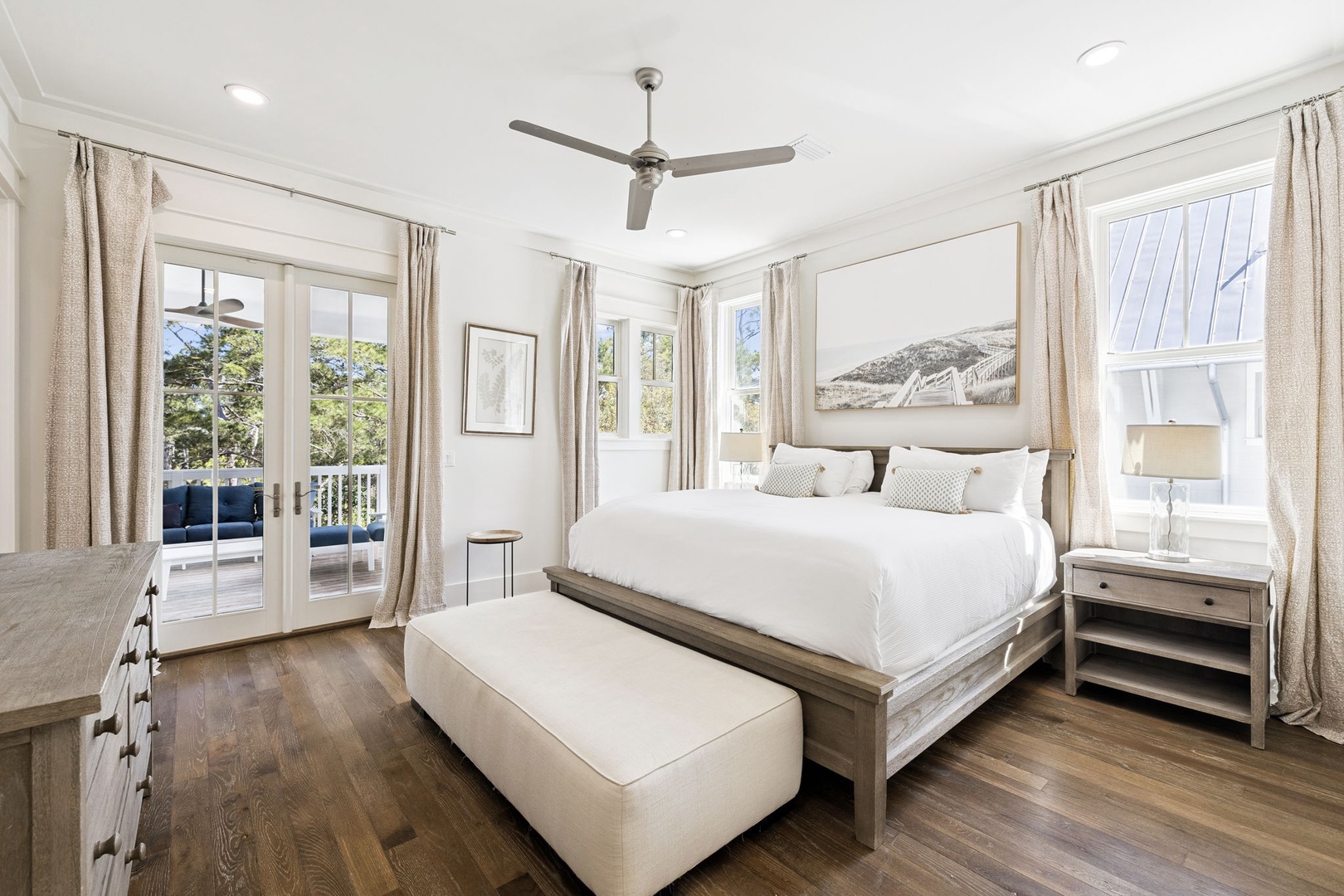 Rest in your serene bedroom where crisp white linens meet coastal charm, with a private balcony inviting morning light into your peaceful retreat.