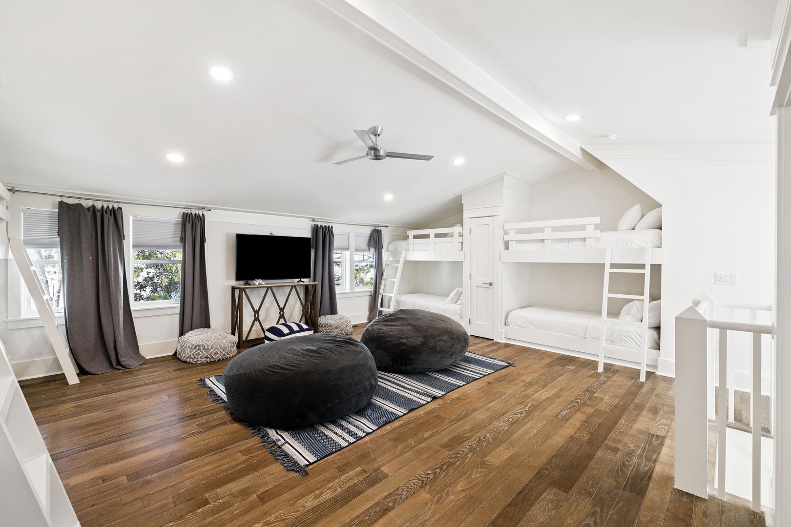 Gather around oversized bean bags for movie nights in your spacious loft bedroom featuring cozy bunk beds and warm hardwood floors.