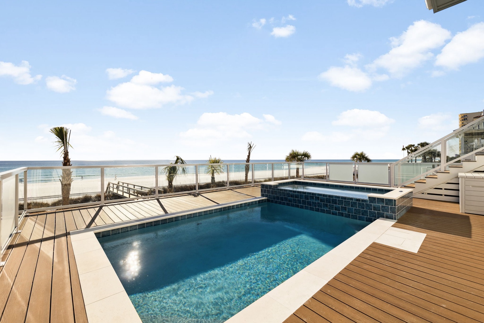 Beachfront pool deck with panoramic ocean views and direct beach access via private boardwalk.