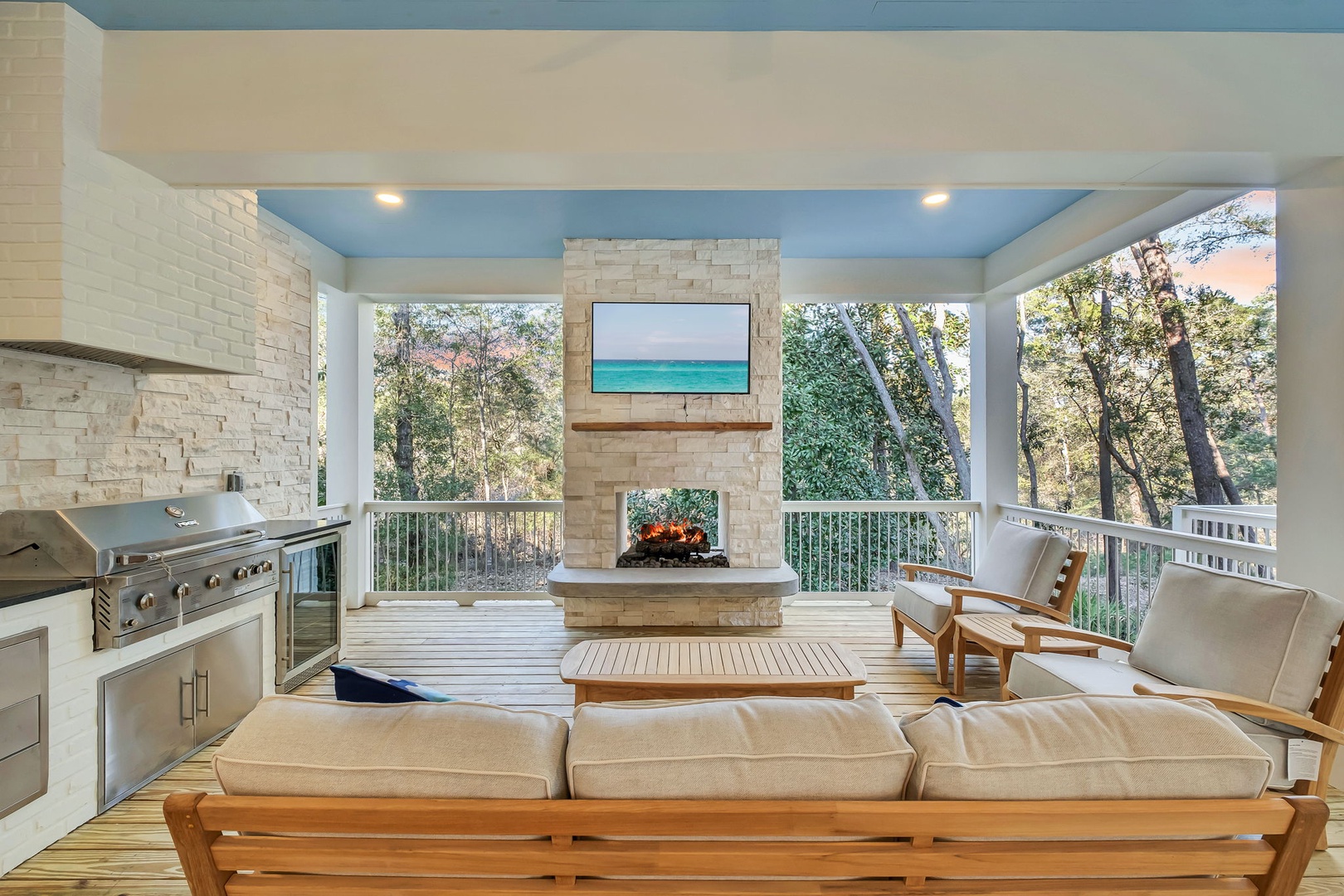 Relax in your covered outdoor living room with fireplace, full kitchen, and peaceful tree views—perfect for entertaining or quiet evenings.