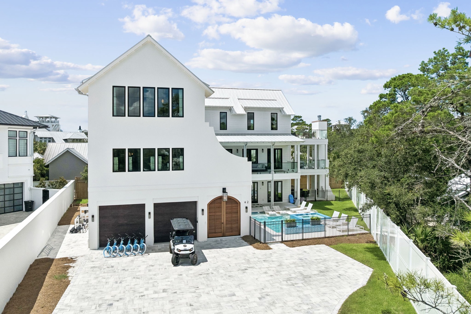 This stunning modern farmhouse features a private pool, spacious outdoor entertaining areas, and golf cart access—all set against a backdrop of natural greenery and coastal charm.