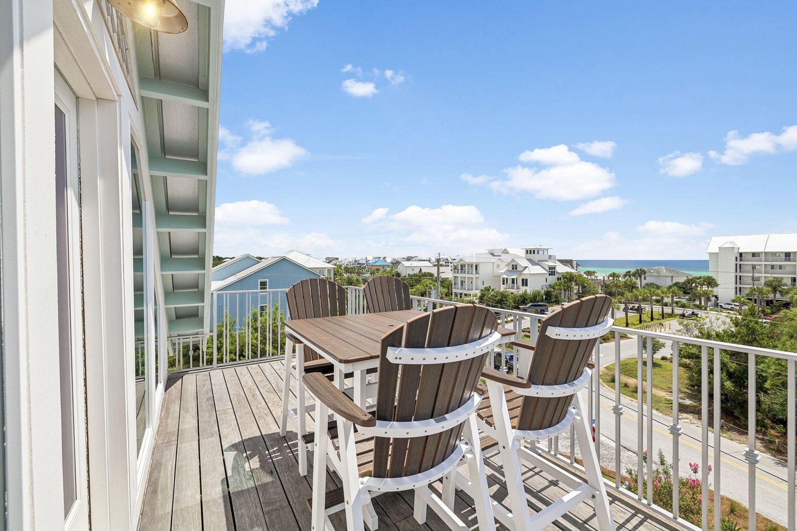 Step onto your private balcony and settle into cozy Adirondack chairs, where you'll savor coastal breezes, swaying palms, and a partial view of the shimmering sea beyond the neighborhood.