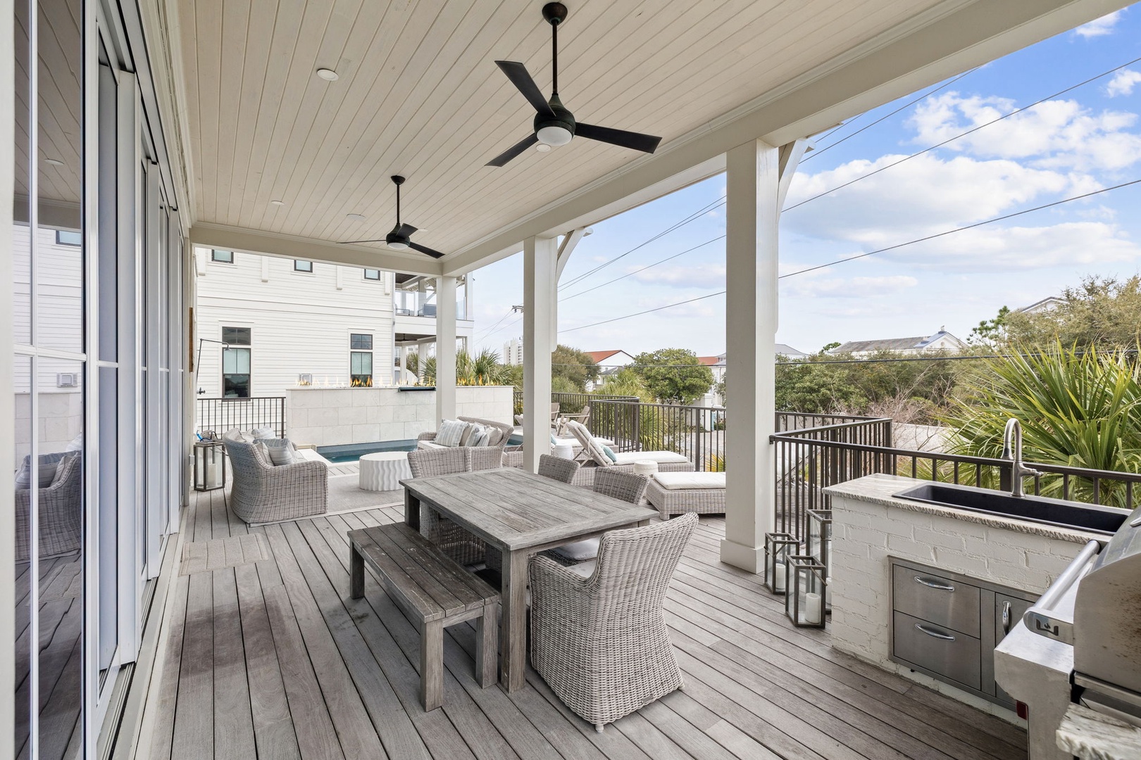 Your expansive covered deck combines dining and lounging spaces, complete with ceiling fans and outdoor kitchen for perfect entertaining.