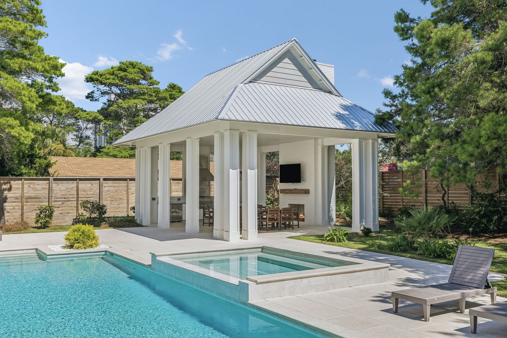 A pristine pool and elegant pavilion set the stage for your sunny vacation days, framed by lush greenery and complete with a sunbed for soaking up the warmth.
